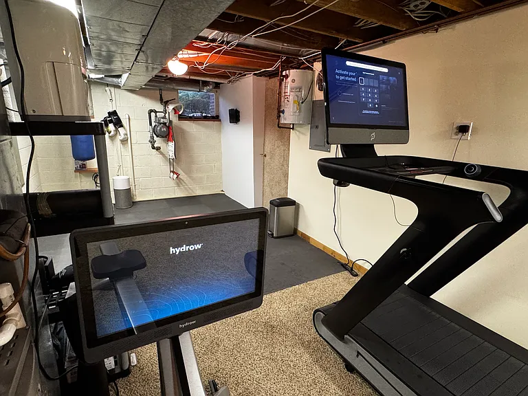 Basement gym with Hydro and Peloton Tread Plus treadmill (looking from midpoint towards front of house).