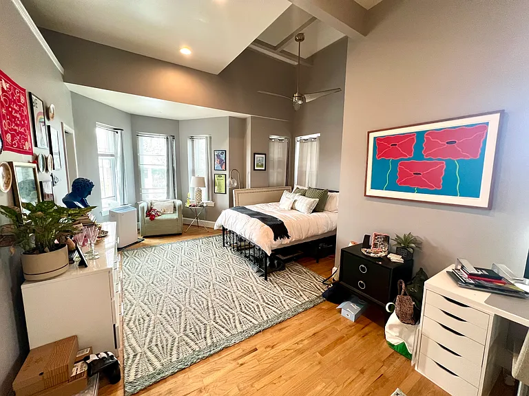 Primary bedroom featuring large walk-in closet, exposed brick, 15 foot plus ceilings, and with en-suite bathroom.