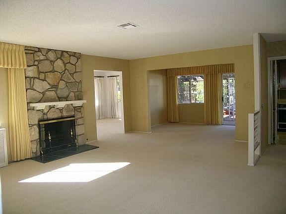 Sunny and spacious living room with fireplace and yard views