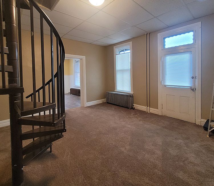 Living room featuring new paint and carpet. View of front door and entrance into kitchen.