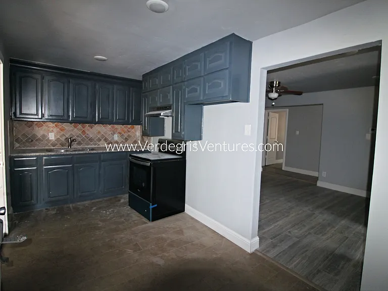 The kitchen is modest in size yet functional, featuring granite counters, stainless steel sink and appliances, a west_facing window for natural light, and direct access to the carport