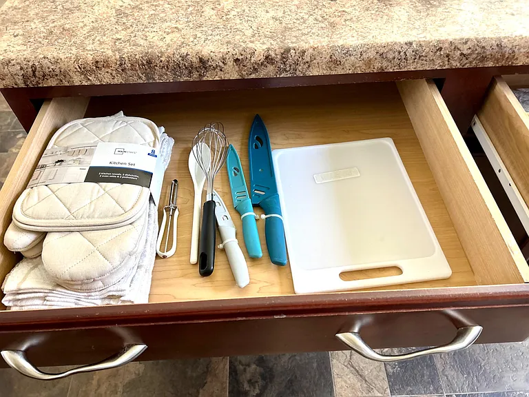 Kitchen drawers offer organized storage and include essential cooking tools like knives, cutting board, and utensils.