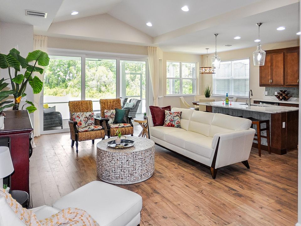 Your light-filled great room has a vaulted ceiling, wood floors and a view of the waterway and greenery outside.