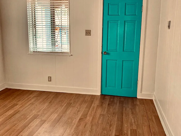 living room with south and west windows providing lots of natural light, original Vegas, white walls and a turquoise front door.