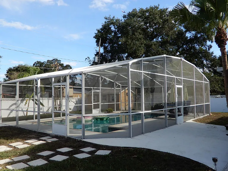Large screened custom pool with pool cleaning equipment and plenty of cool deck.