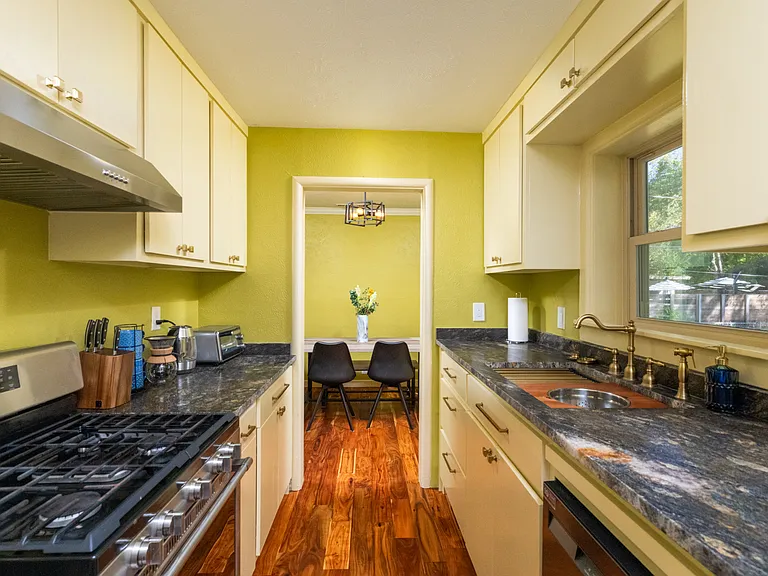 Bright, fully equipped kitchen with stainless steel appliances, warm wood floors, and modern yellow cabinets_perfect for cooking and relaxing at home.