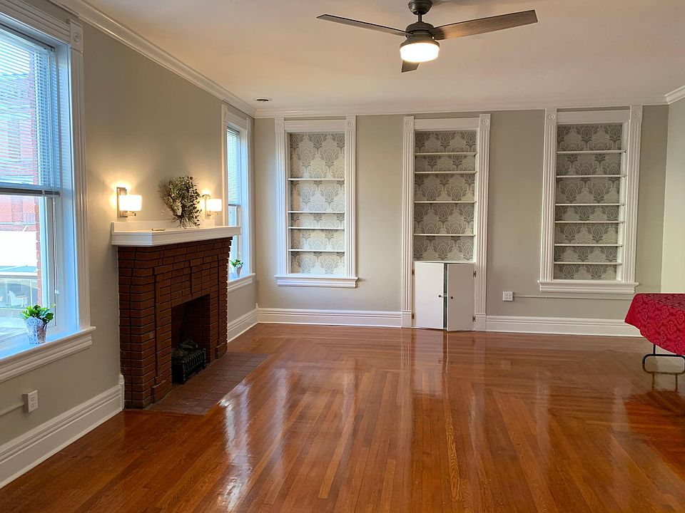 The end wall of the living room is furnished with three panels of white painted shelves. They are newly backed with neutral metallic wallpaper to blend with the grey walls and white trim. Lots of storage for books, knicknacks and framed photographs.