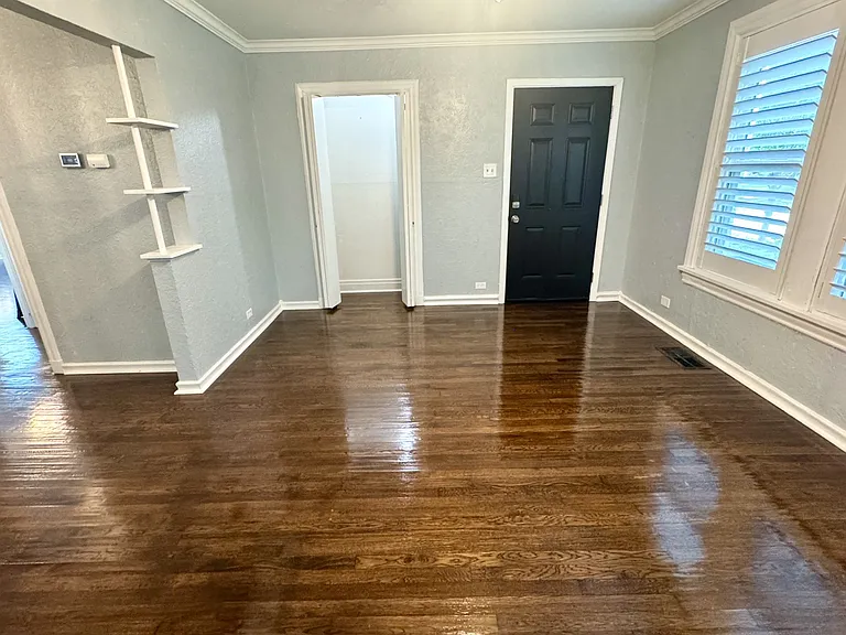 View from the living room, gorgeous hand scraped hardwood floors, front door of duplex, and custom wood plantation shutters.
