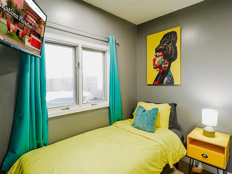 modern space highlighted by a vibrant yellow painting against a cool gray wall, complemented by a chic lamp and a TV for a blend of style and entertainment.