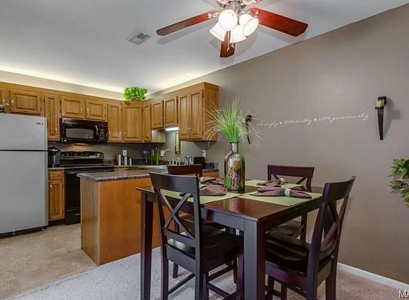 Dining and kitchen area with ceiling fan and light.