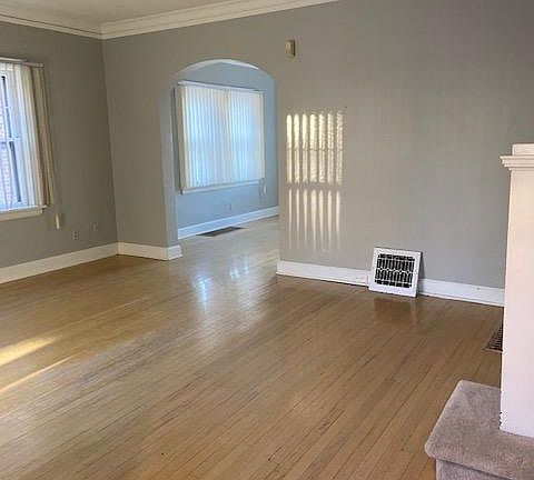 Hardwood floors and two sets of windows in this charming Living room with arch doorways, and crown molding.