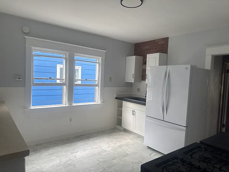 Spacious kitchen featuring granite countertops, ample cabinet space, and a full-size refrigerator and stove.