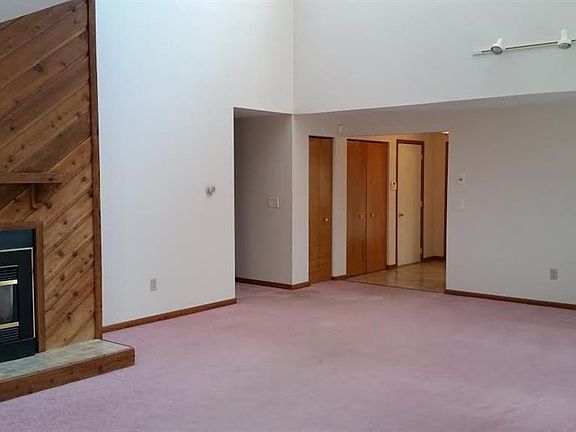 Large living room and dining room combination with a gas fireplace and vaulted ceiling.