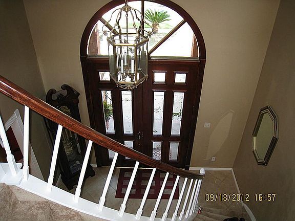 Double doors in foyer with 2 story ceiling and curved staircase