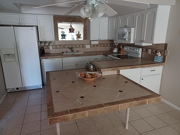 Kitchen is stocked with what you need to cook and eat except food. There are 4 chairs (not in picture) that fit around the table in the foreground.