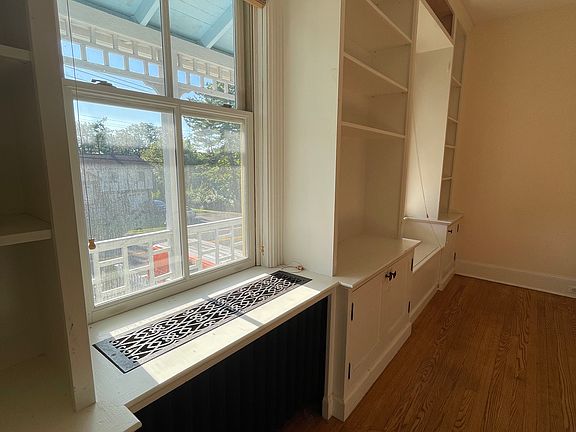 living room with details like built-in bookcase and iron radiator cover and storage loveseat (at other end)