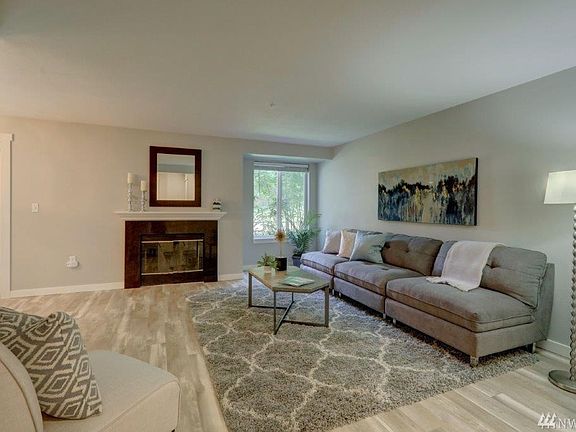 Another view of living room with wood burning fireplace. 