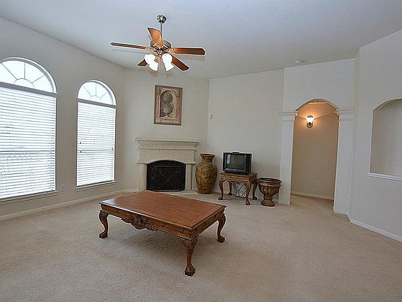 Spacious family room with art niche, wall -of-windows, corner wood burning fireplace, carpet and ceiling fan.