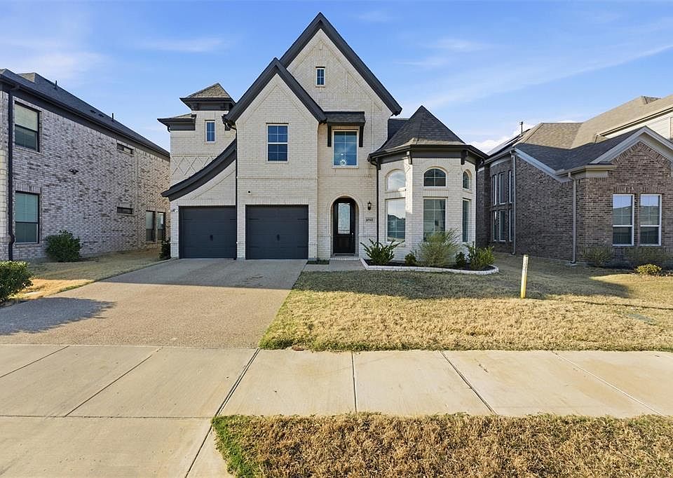 French provincial home featuring driveway, brick siding, an attached garage, and a front lawn
