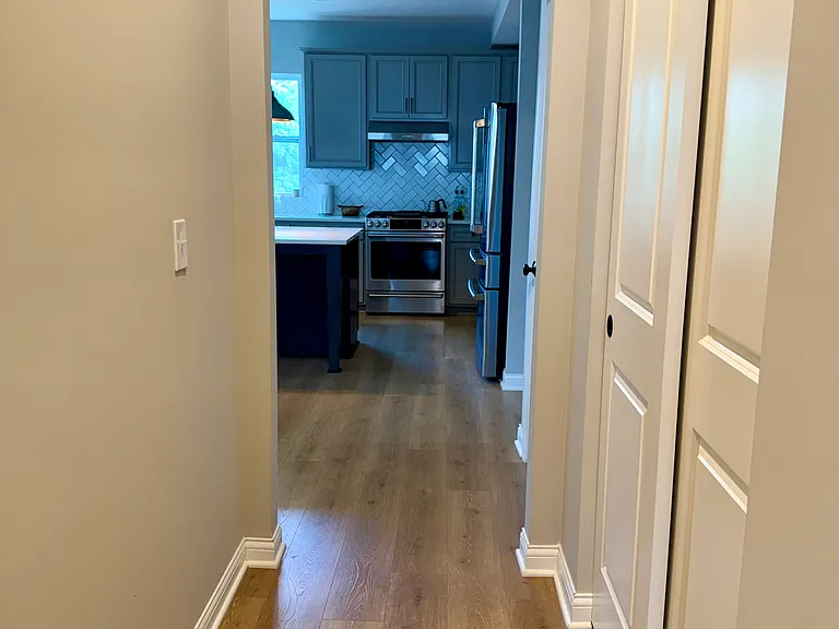 Hallway leading from front door to open concept kitchen, dining, and living space