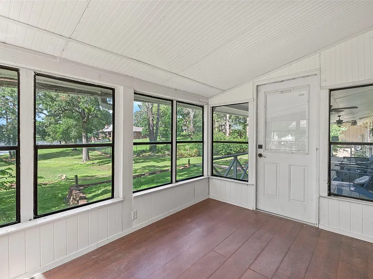 Enclosed sunroom featuring multiple large windows, wood-finish flooring, and white paneled walls and ceiling