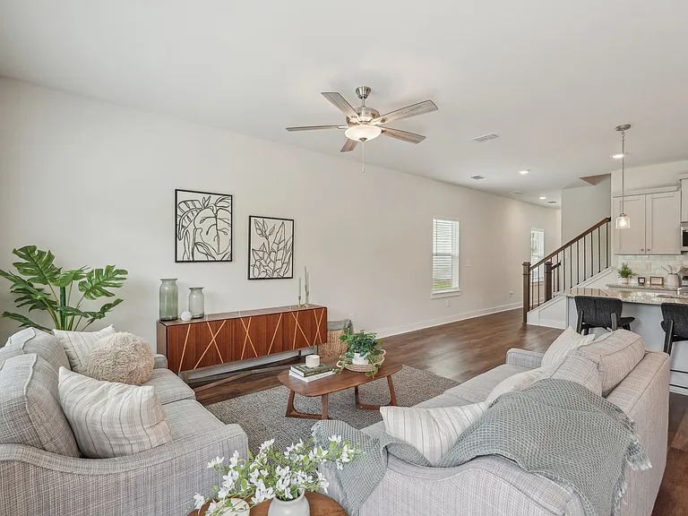 View of the living room area featuring an open staircase and refined dining space.