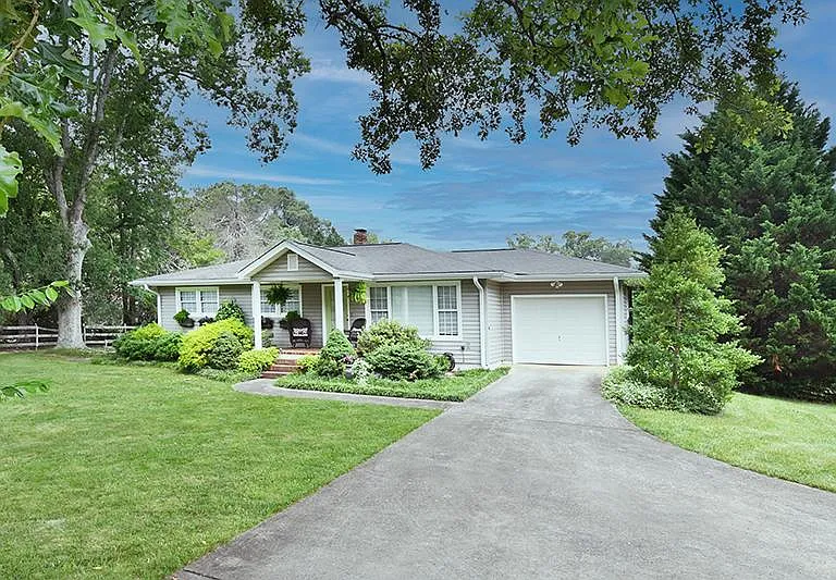 Oak trees frame the front of the home. Landscaping is provided.