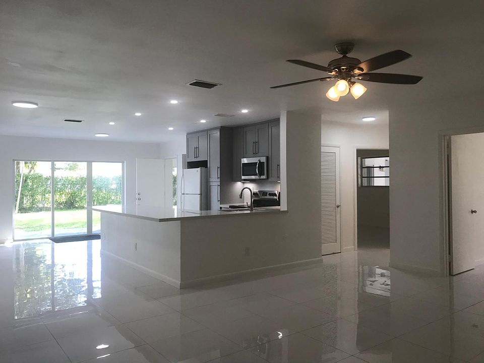 New kitchen with quartz countertop in open living dining area with wide hurricane proof sliding glass doors to the backyard.
