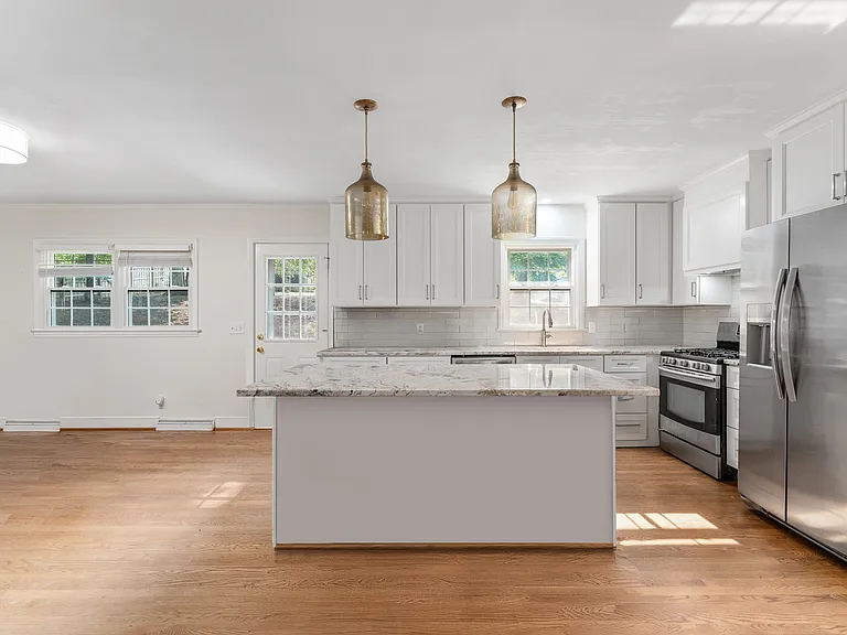 Kitchen is fully renovated with new white cabinets, stainless appliances, island and designer lighting.