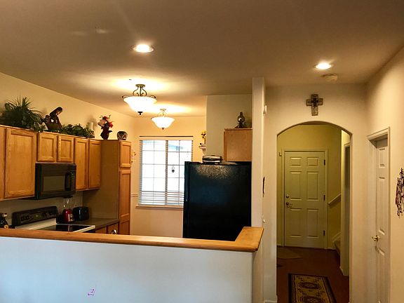 View of kitchen to the left from the dining room/living room, hallway leading to garage door, front entrance to townhome on left, stairway going up to bedrooms on right, and door to the right is laundry room on main level.