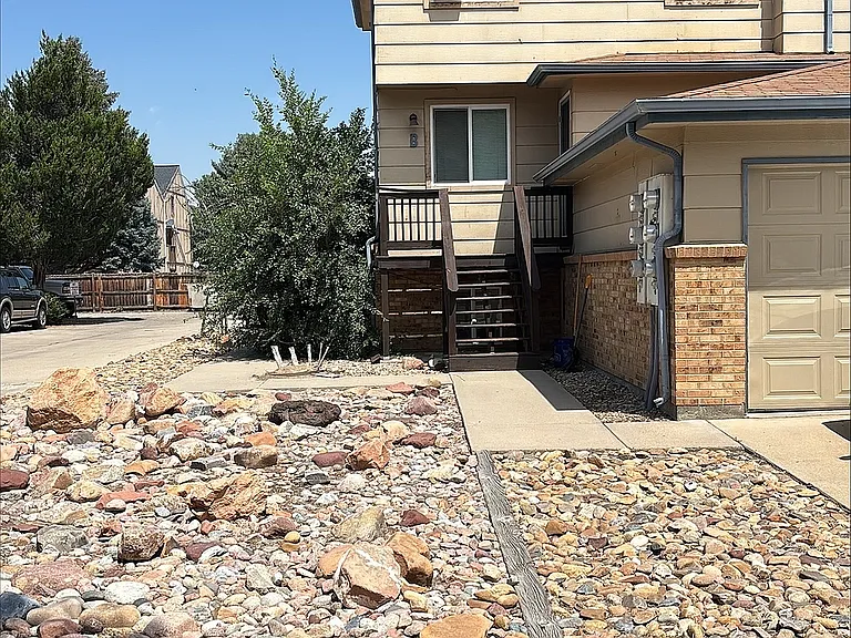 Charming townhouse exterior with a rustic rock garden landscape, nestled in a serene suburban setting.