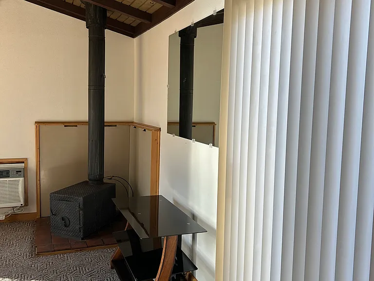 Partial view of living area with wood stove and glass door leading to fenced patio area.