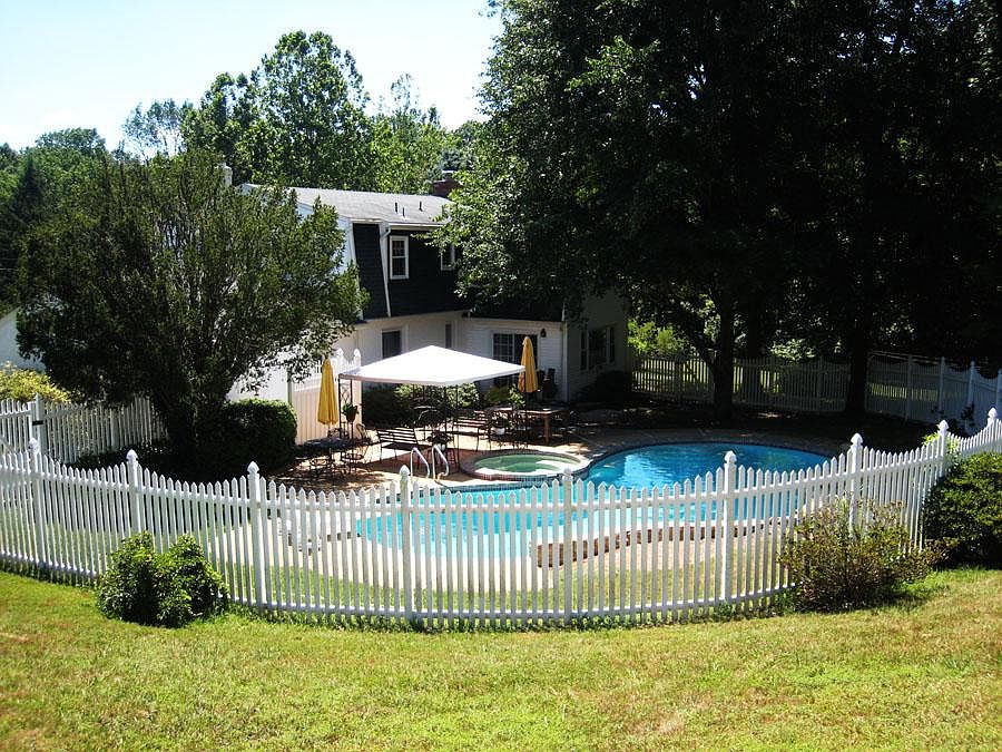View of back of house, deck, pool, fenced in area.