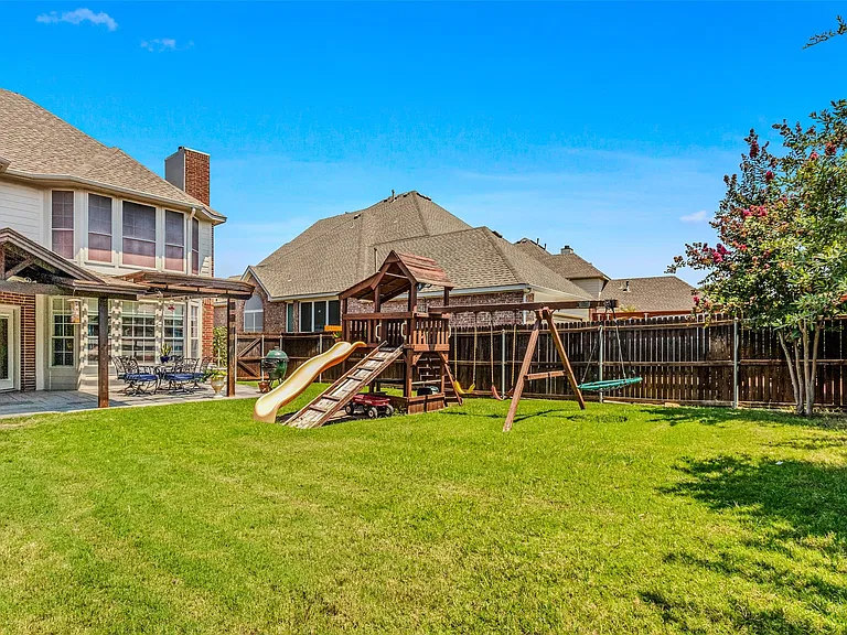 Expansive backyard featuring a lush lawn, a wood fence, and a patio area with a pergola