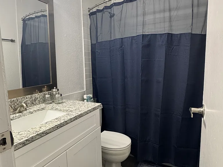 Bathroom features a granite-top vanity and subway tile shower with a relaxing soaker tub.