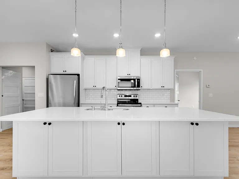 Modern kitchen with sleek white cabinetry, stainless steel appliances, and elegant pendant lighting over a spacious island. Modern kitchen with sleek white cabinetry, stainless steel appliances, and elegant pendant lighting over a spacious island.