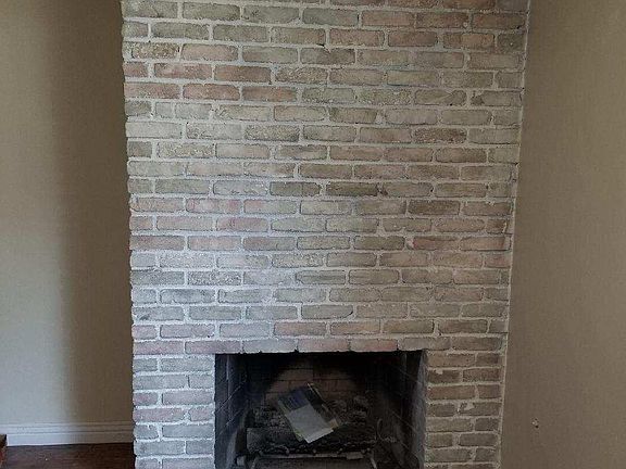 Lovely brick fireplace in living room; hardwood floor.
