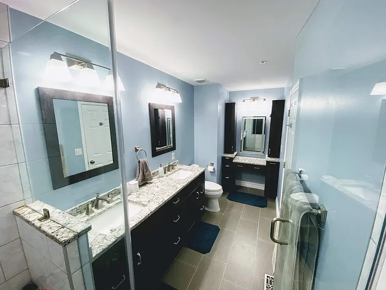 Fully renovated custom master bathroom with walk-in river rock shower, recessed storage, tile floor, double sinks, granite countertops, spacious cabinets and custom vanity with backlit mirror.