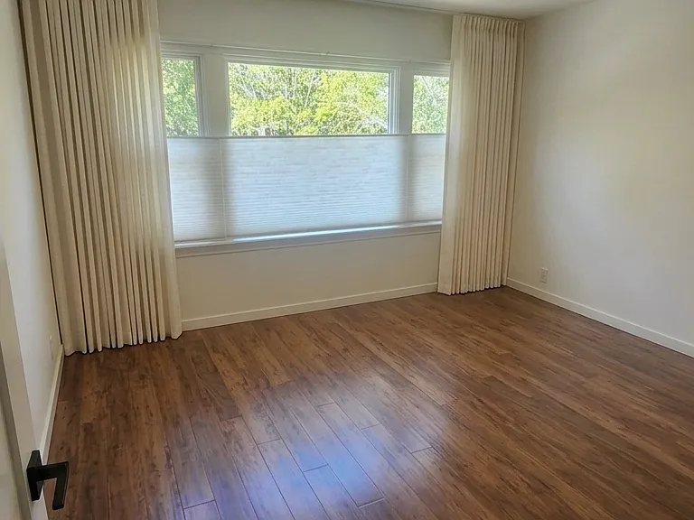 Front bedroom. South-facing / street-facing with custom, light-filtering, up/down privacy blinds and ceiling-track linen curtains.