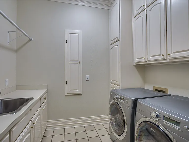 The laundry room is a good size. Offers a sink, abundant cabinetry, hanging space, ironing board, and tile flooring. Note: It does NOT have a washer and dryer as shown in the picture.