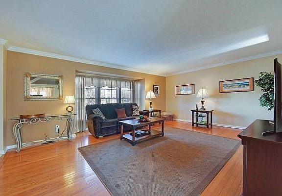 Spacious living room featuring hardwood floors, neutral tones, crown molding, Bay window.