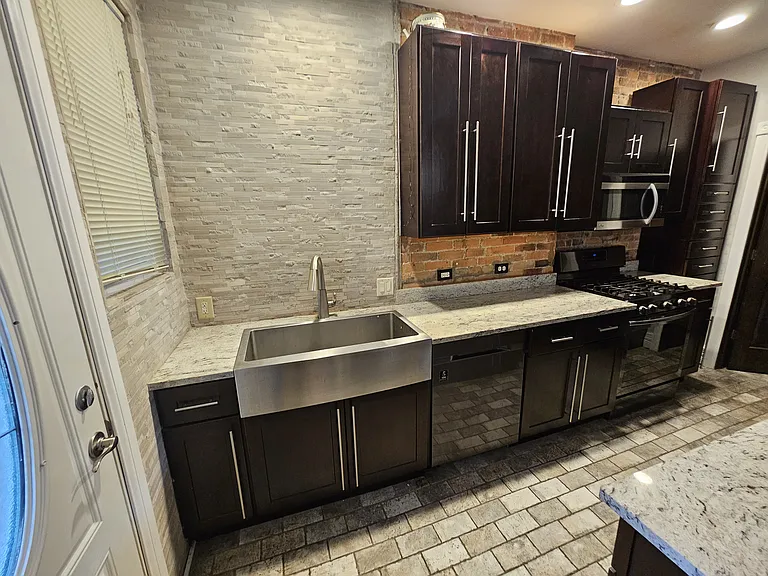 Beautiful intricate backsplash and a very large stainless steel Amish sink.
