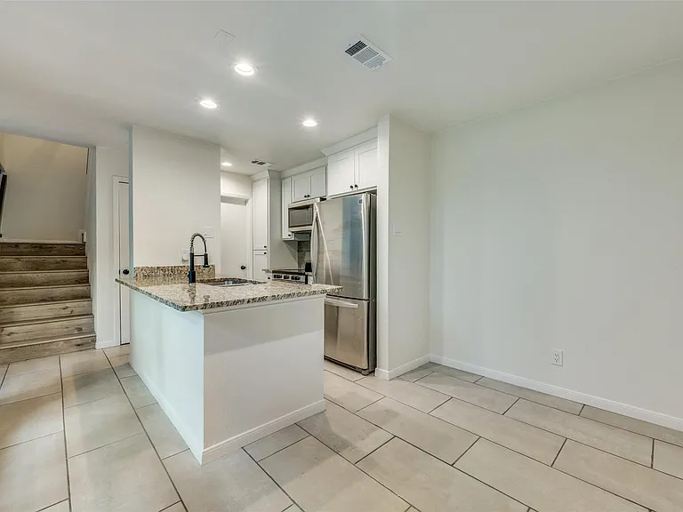 Contemporary kitchen island featuring a granite countertop, undermount sink, and matte black faucet