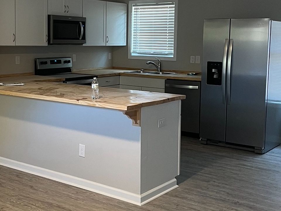 Open floor plan living area and kitchen with stainless steel appliances noted oven,microwave combination with dishwasher and refrigerator. Butcher block countertops.