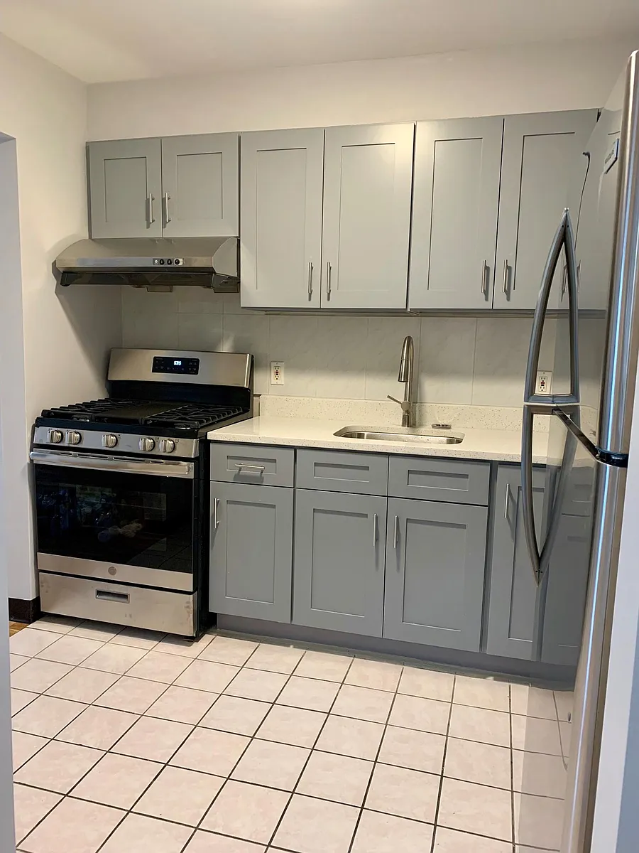 Fully remodeled kitchen with new cabinets, quartz countertop, brand-new stainless steel appliances, and vented range hood. - 43-71 161st St #2