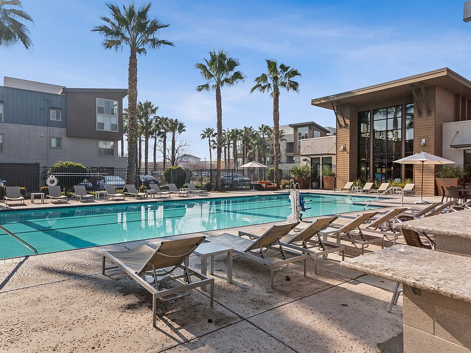 Aspire Apartments Tracy California Luxury Living A large swimming pool in front of a building with palm trees.