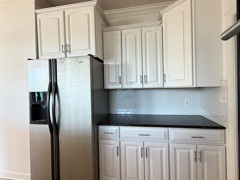 Extra tall cabinetry beside the full-size fridge adds hidden storage for bulk items or small appliances.
