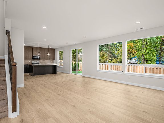 Open great room with laminate floors and wide windows for natural light.