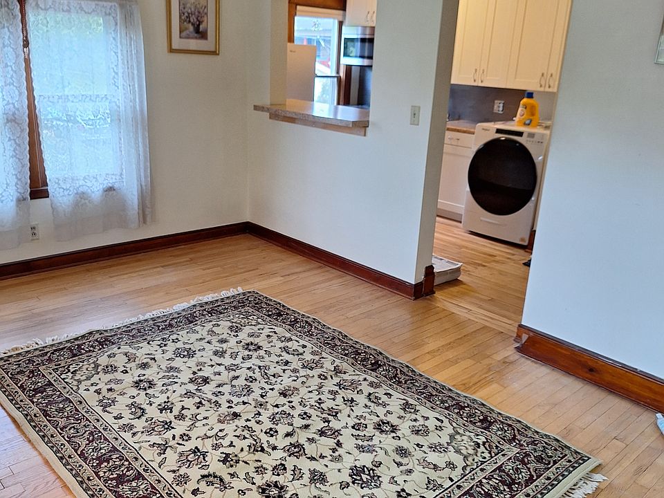 Living room: oak hardwood floors, pass-through interior window to kitchen. Six windows on east, north, and west side of house.