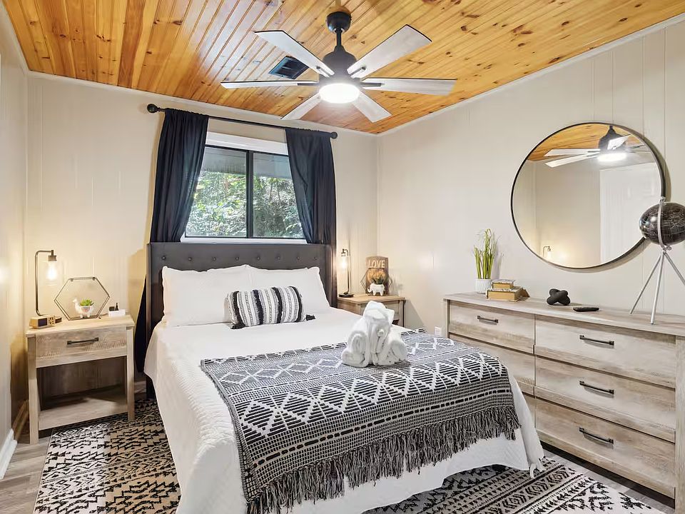 Room A _ Private furnished bedroom featuring a queen bed, natural wood ceiling, large dresser, and cozy lighting. Bright and stylish space with modern decor and peaceful mountain vibes _ perfect for extended stays.